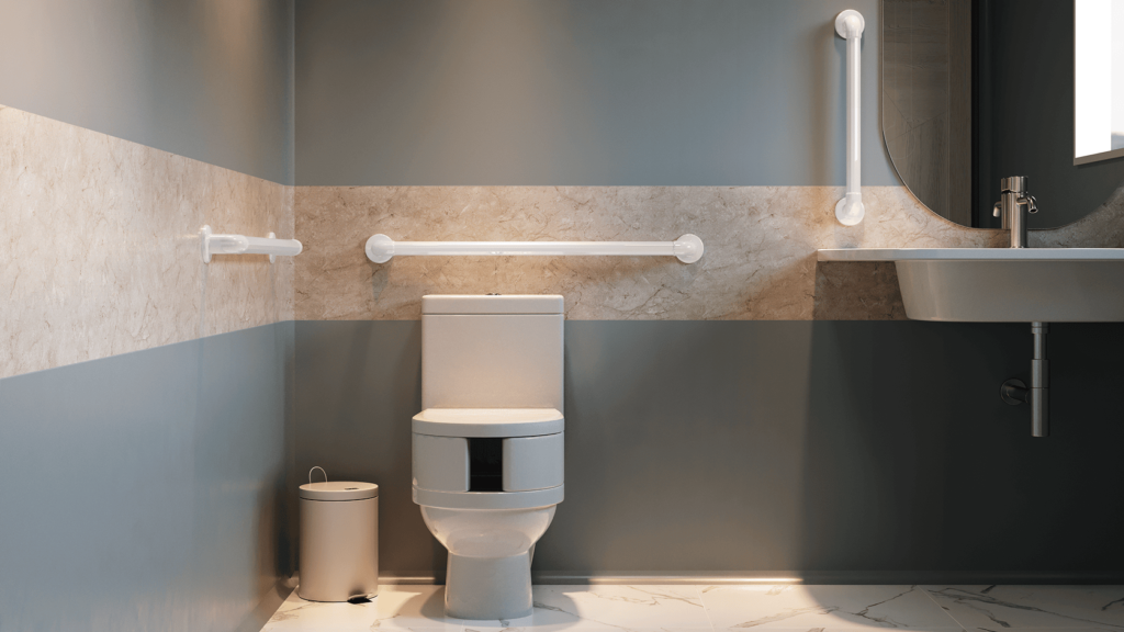 Banheiro com paredes em dois tons e faixa de revestimento central. Ao centro há um vaso sanitário com barras de apoio horizontal atrás e lateral. À direita, pia suspensa com torneira metálica e barras de apoio vertical próxima. À esquerda, lixeira com tampa. Piso claro com veios e iluminação uniforme.